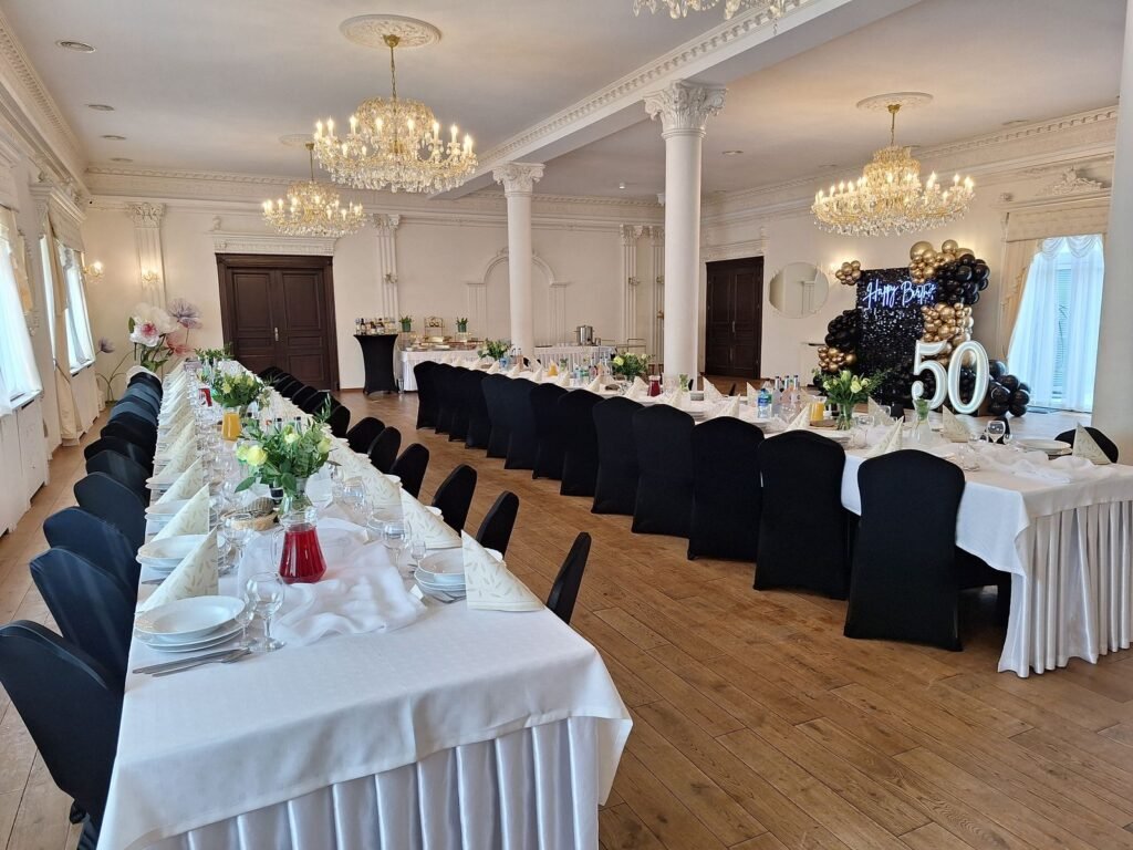Sala z czarnymi pokrowcami na krzesłach i ścianką na 50. urodziny – jubileusz w Parzęczewie