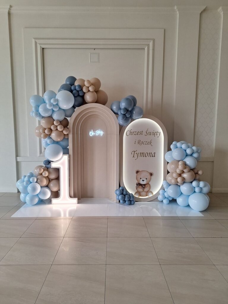 Ścianka z łukami w beżu, błękitne balony i świecąca cyfra 1 – roczek w Poddębicach